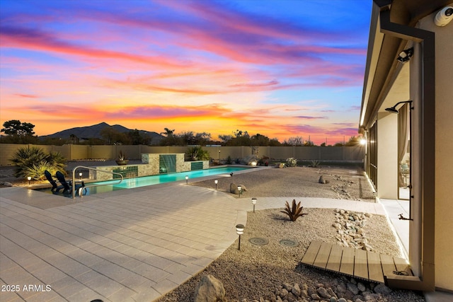 pool at dusk featuring a mountain view and a patio area