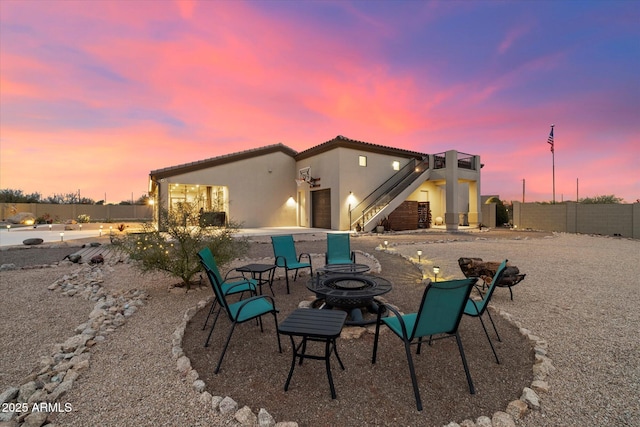 back house at dusk featuring a patio and an outdoor fire pit