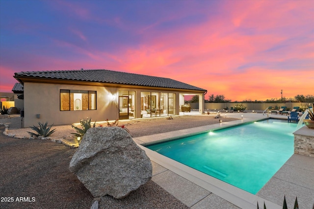 pool at dusk with a patio area