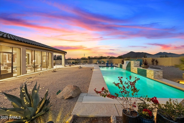 pool at dusk featuring a patio and a mountain view