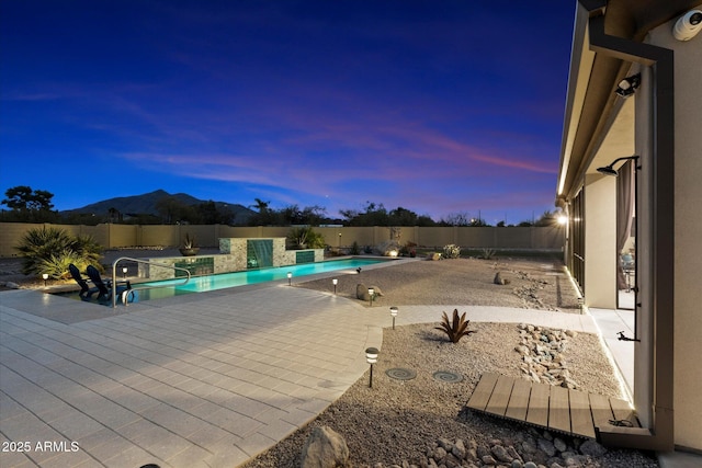 pool at dusk with a mountain view and a patio