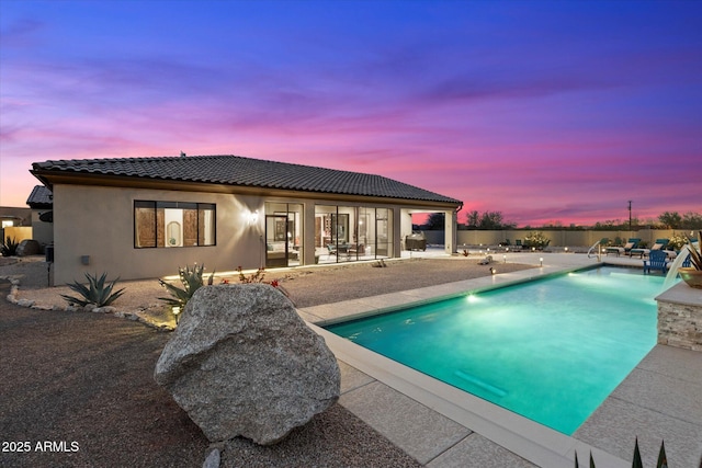 pool at dusk featuring a patio