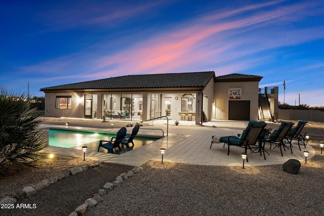 back house at dusk featuring a patio area