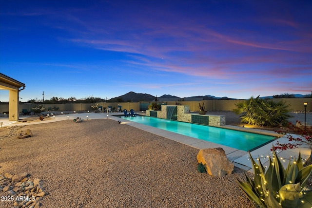 pool at dusk featuring a mountain view and a patio area