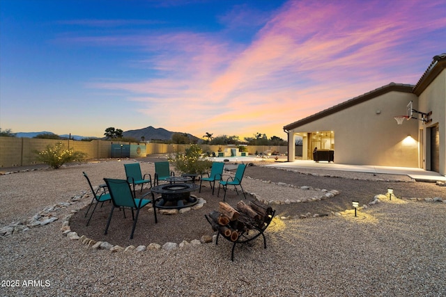 patio terrace at dusk featuring a mountain view and a fire pit