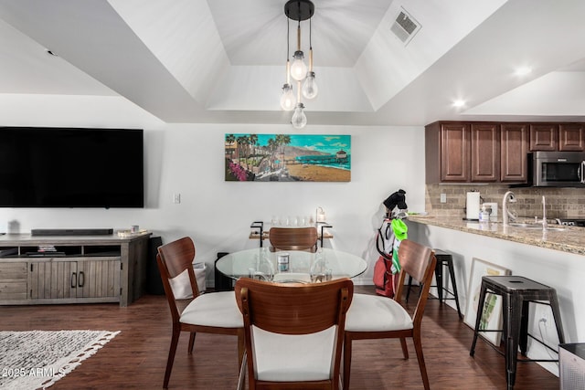 dining space featuring a raised ceiling, sink, and dark wood-type flooring