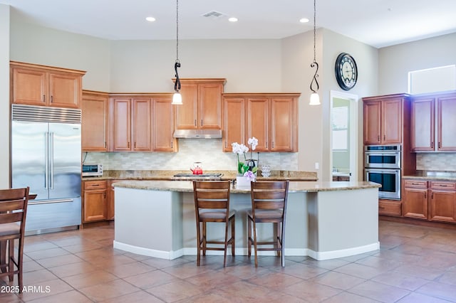 32731 N 74th Way, Scottsdale, AZ 85266 - kitchen featuring stainless steel appliances, under cabinet range hood, an island with sink, tasteful backsplash, and decorative light fixtures