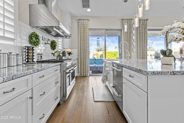 kitchen featuring white cabinetry, wall chimney range hood, decorative light fixtures, and high end stove