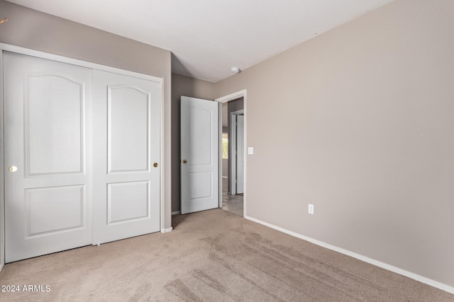 unfurnished bedroom with light carpet and a closet