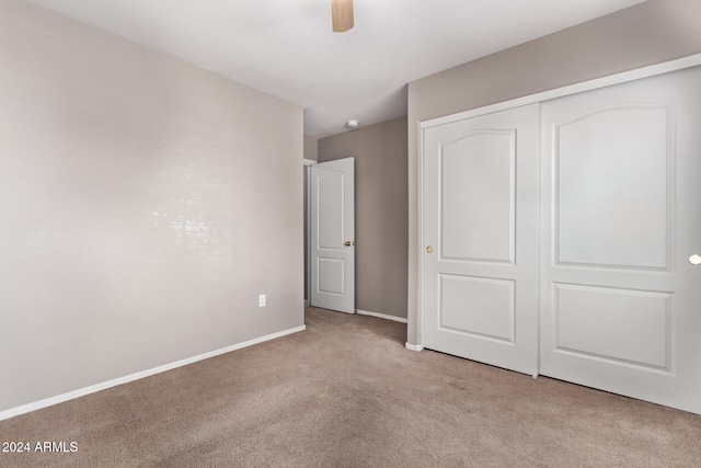 unfurnished bedroom featuring ceiling fan, light carpet, and a closet