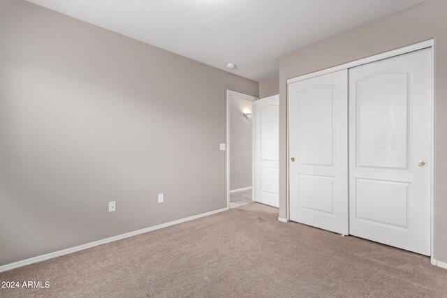 unfurnished bedroom with light carpet and a closet