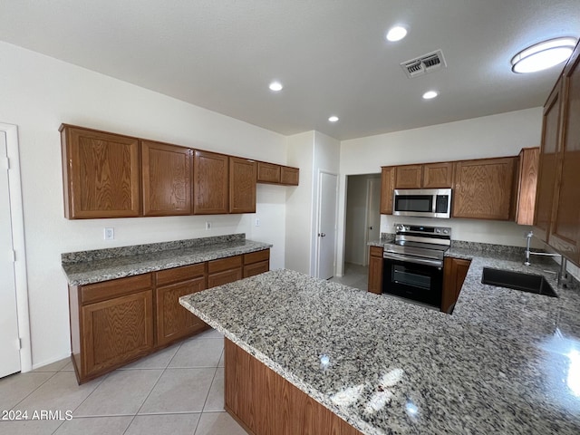 kitchen featuring kitchen peninsula, sink, light tile patterned flooring, appliances with stainless steel finishes, and light stone counters