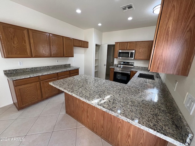 kitchen with light stone countertops, appliances with stainless steel finishes, and kitchen peninsula