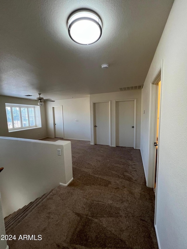 hallway featuring carpet and a textured ceiling