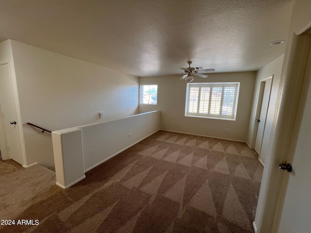 spare room featuring ceiling fan, carpet, and a textured ceiling