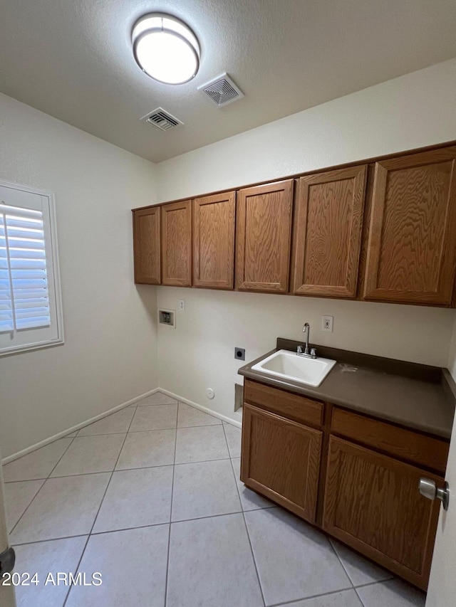 clothes washing area featuring cabinets, light tile patterned floors, hookup for a washing machine, electric dryer hookup, and sink