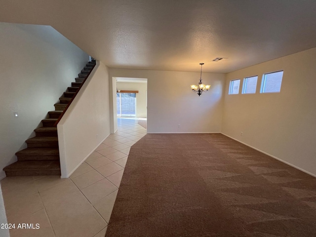 carpeted spare room featuring a textured ceiling and an inviting chandelier