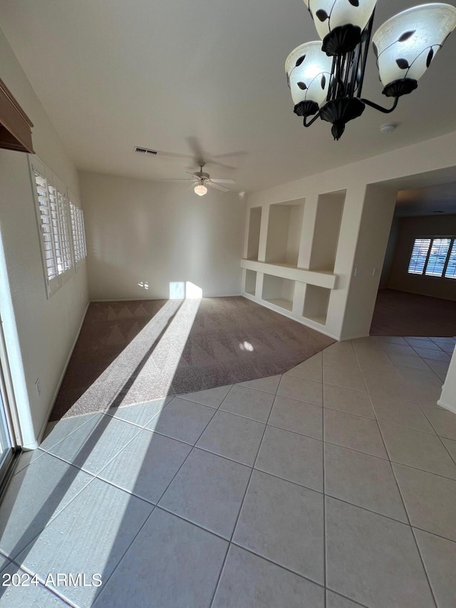 spare room featuring ceiling fan with notable chandelier, plenty of natural light, and light tile patterned floors