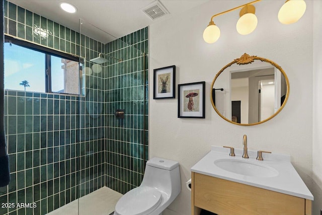 bathroom featuring vanity, toilet, and tiled shower