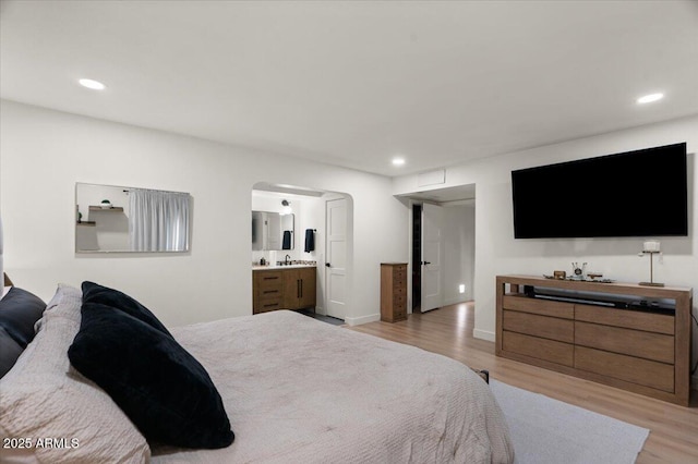 bedroom featuring light hardwood / wood-style flooring and ensuite bath