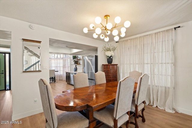 dining space with hardwood / wood-style floors, a textured ceiling, and a chandelier