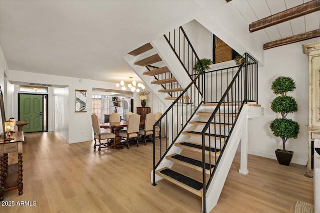 stairway with a notable chandelier, hardwood / wood-style flooring, wood ceiling, and lofted ceiling with beams