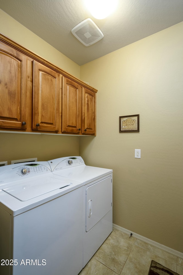 laundry area featuring washing machine and clothes dryer, visible vents, cabinet space, and baseboards