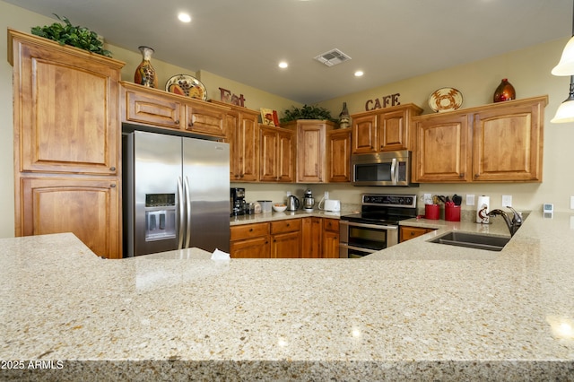 kitchen featuring light stone countertops, visible vents, appliances with stainless steel finishes, and a sink