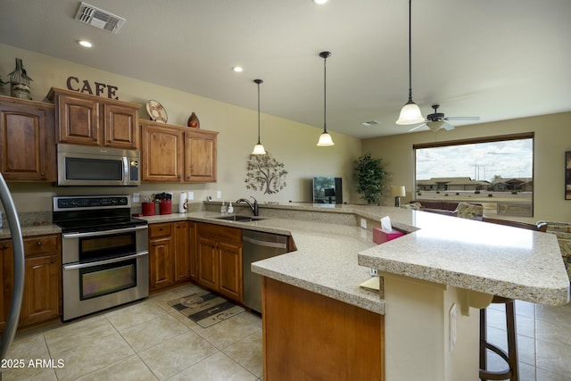 kitchen featuring a sink, hanging light fixtures, visible vents, and stainless steel appliances