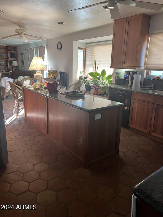 kitchen with ceiling fan, sink, a center island, black dishwasher, and a textured ceiling