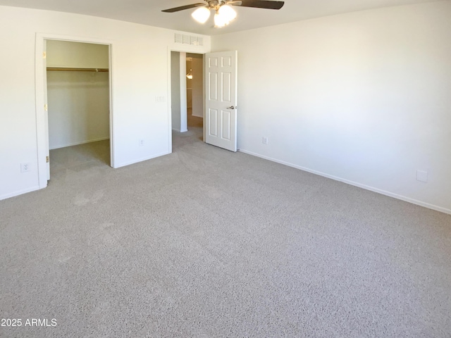 unfurnished bedroom with light carpet, ceiling fan, a walk in closet, and a closet