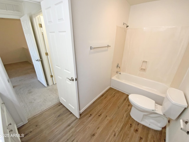 bathroom featuring wood-type flooring, shower / tub combination, and toilet