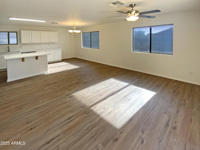 unfurnished living room with ceiling fan with notable chandelier, hardwood / wood-style flooring, and sink