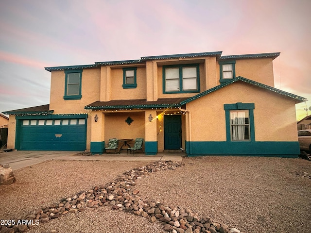 view of front of home with concrete driveway, an attached garage, and stucco siding