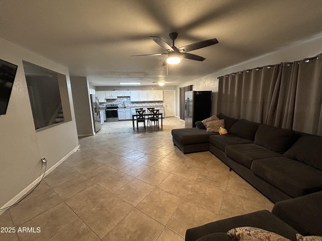 living room with ceiling fan, stairway, baseboards, and light tile patterned floors