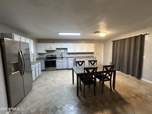 kitchen featuring visible vents, appliances with stainless steel finishes, a sink, under cabinet range hood, and backsplash