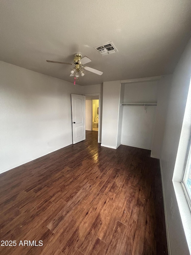 unfurnished bedroom with a ceiling fan, a closet, visible vents, and dark wood finished floors