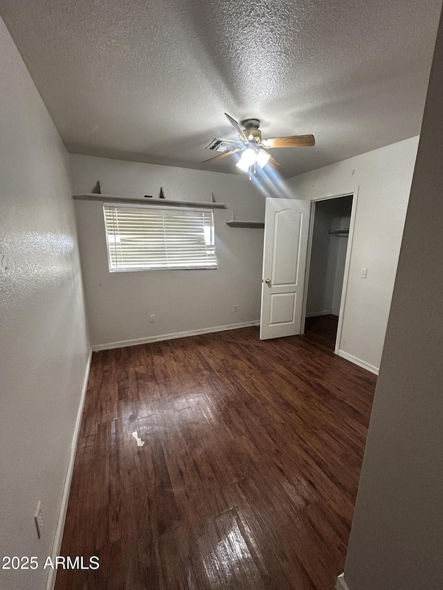 unfurnished bedroom featuring a closet, ceiling fan, a textured ceiling, baseboards, and hardwood / wood-style flooring