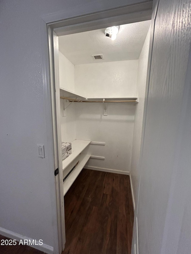 spacious closet featuring dark wood-type flooring and visible vents