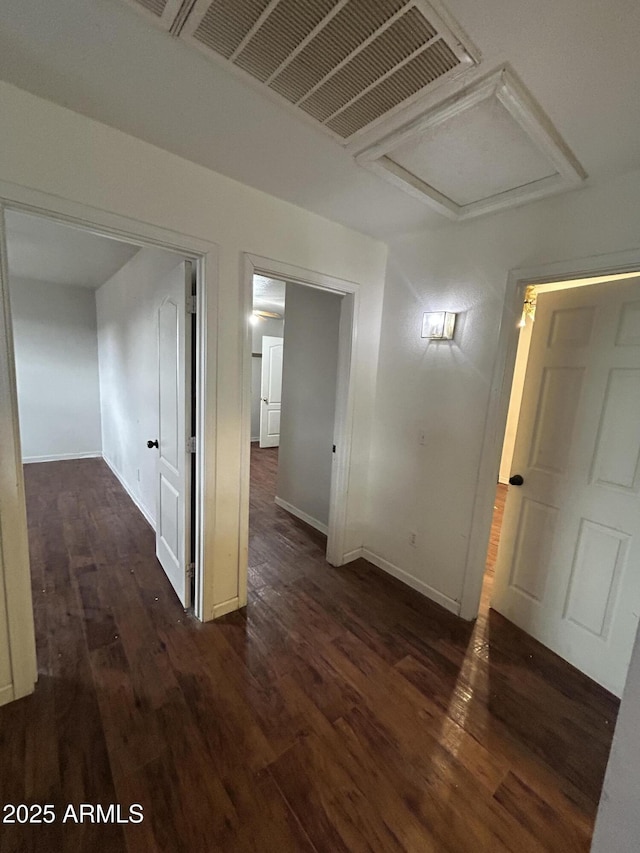 hallway featuring visible vents, dark wood finished floors, attic access, and baseboards