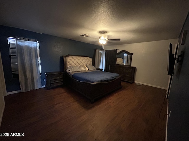 bedroom with baseboards, visible vents, a ceiling fan, dark wood-style flooring, and a textured ceiling