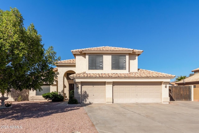 mediterranean / spanish house featuring driveway, a tile roof, fence, and stucco siding