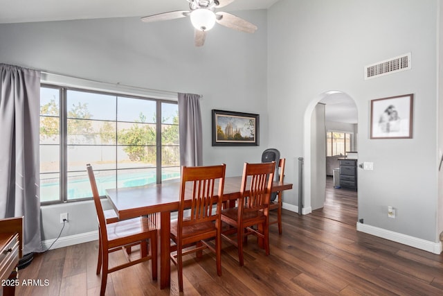 dining area featuring arched walkways, high vaulted ceiling, visible vents, baseboards, and dark wood-style floors