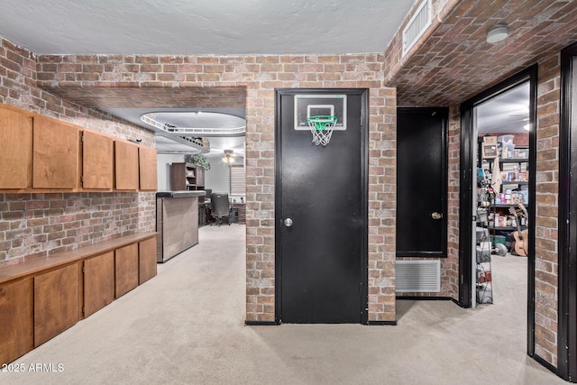 corridor featuring brick wall, visible vents, and light colored carpet