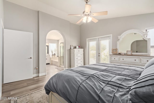 bedroom featuring arched walkways, baseboards, lofted ceiling, light wood-style flooring, and access to outside