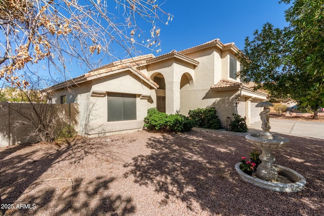 view of front of home featuring a tiled roof, fence, and stucco siding