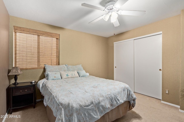 bedroom with a closet, a ceiling fan, and light colored carpet