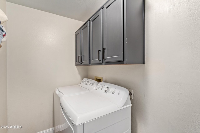 washroom featuring cabinet space, washer and clothes dryer, and baseboards