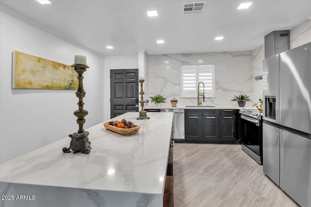 3505 N Miller Rd, Scottsdale, AZ 85251 - kitchen featuring appliances with stainless steel finishes, a sink, light stone countertops, crown molding, and dark cabinets