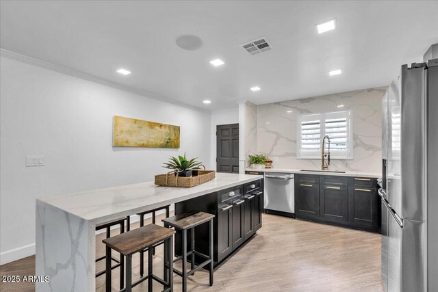 3505 N Miller Rd, Scottsdale, AZ 85251 - kitchen featuring stainless steel appliances, crown molding, dark cabinetry, a kitchen bar, and a center island